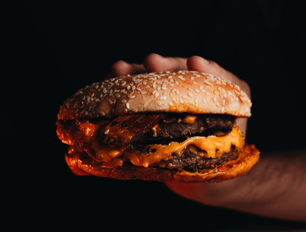 A close-up of a juicy burger being cut in half, showcasing the fresh ingredients and toppings, perfect for midnight cravin…