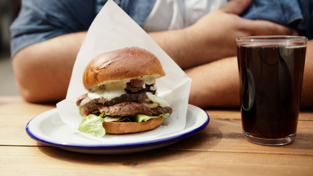 A close-up of a juicy late night burger on a restaurant table with drinks — late night burgers Las Vegas
