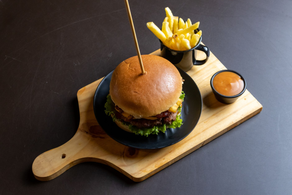 A close-up shot of a gourmet burger plated with fries and dipping sauces. — burgers near Las Vegas Strip