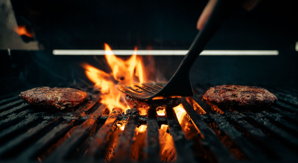 A grill sizzling with burgers, showcasing the grilling cooking technique in action. — what makes a good burger