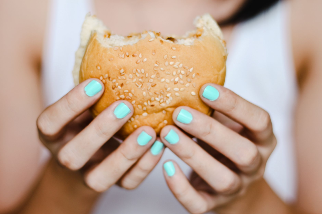 A hand holding a classic cheeseburger with a bite taken out of it. — choosing the best burger