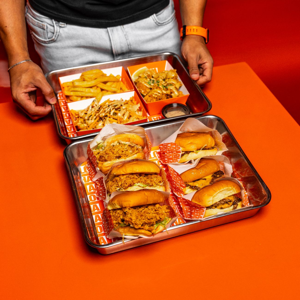 A smiling child holding a mini burger and fries, showcasing the kids menu. — family-friendly burgers Las Vegas
