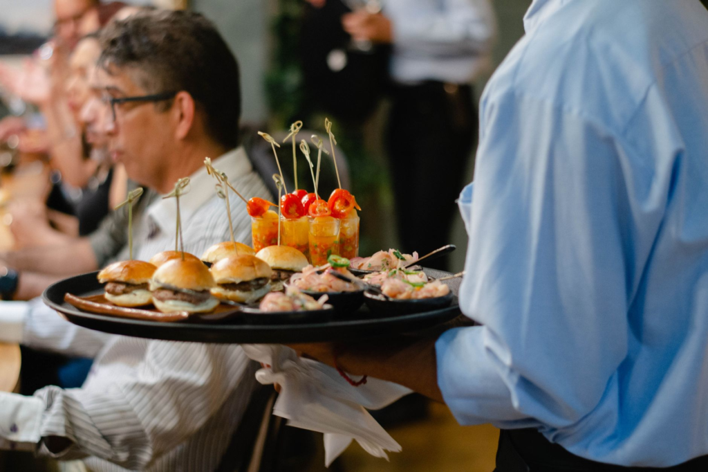 A smiling waiter serving burgers during a special event, emphasizing the community vibe and promotions available. — burg…