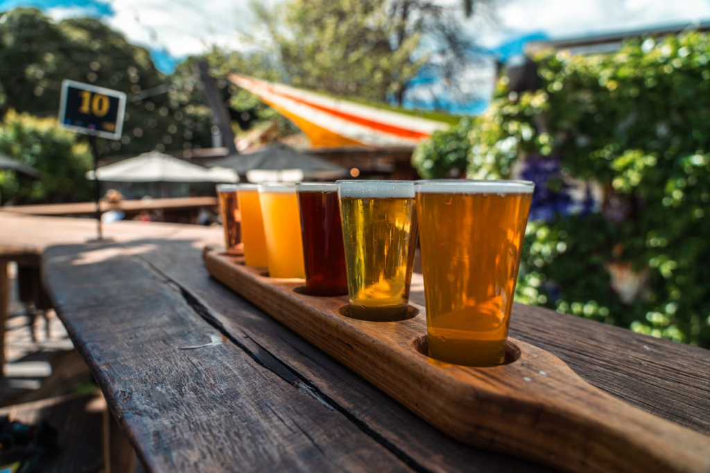 A vibrant outdoor seating area of a Las Vegas brewery on a sunny day with burgers and beers on tables. — burger beer pai…