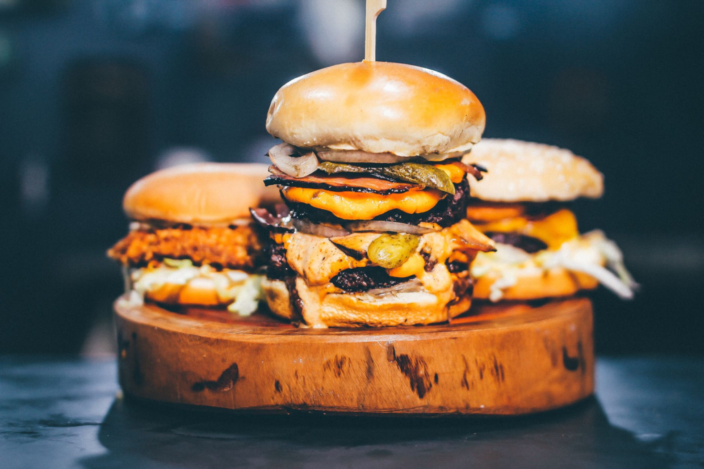An aesthetically pleasing burger stacked high with layers of ingredients and garnished with herbs. — what makes a good b…