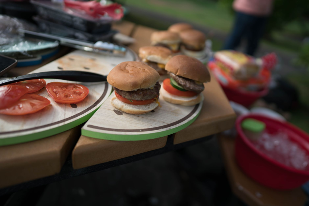 An assortment of fresh burger ingredients, including various types of meat, vegetables, and condiments. — what makes a g…